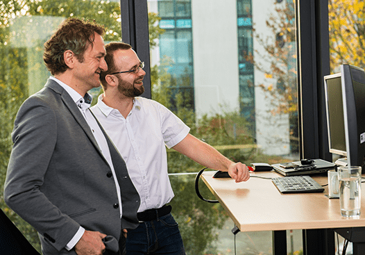 fecher: Ihre Spezialisten hinter der hunter Recruiting Software fecher-Mitarbeiter stehen lachend Steharbeitsplatz Büro