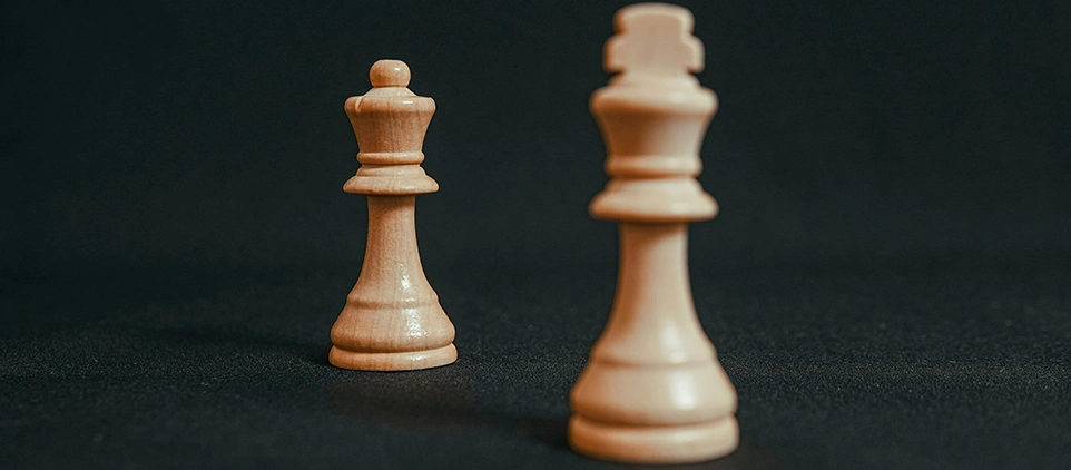 Zwei Schachfiguren vor einem dunklen Hintergrund